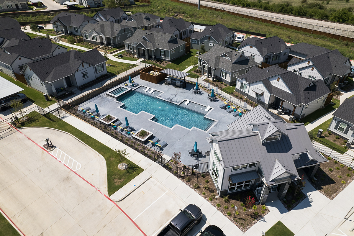 Leasing office with a resort-style pool surrounded by gray and white homes.