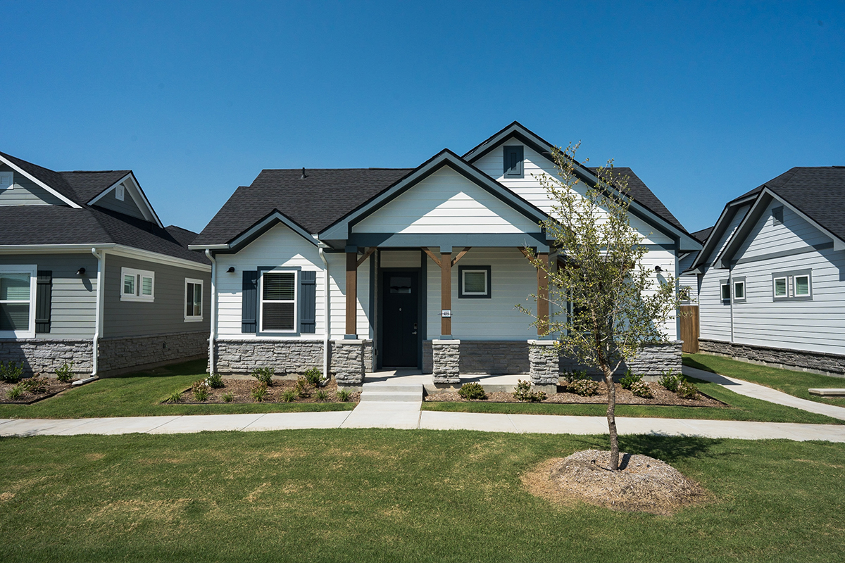 White and gray single family for rent home with greenery and trees.