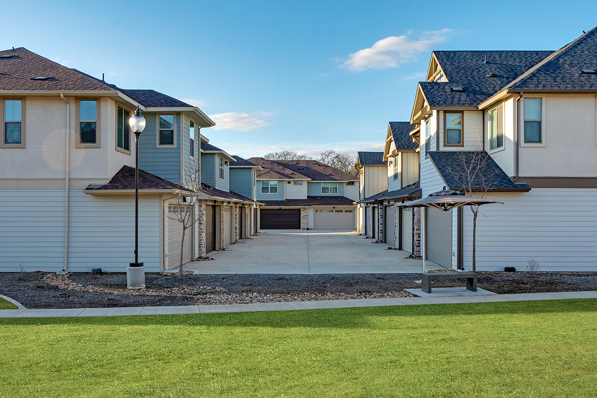 Rows of luxury townhomes surrounded by green grass and a walking path.