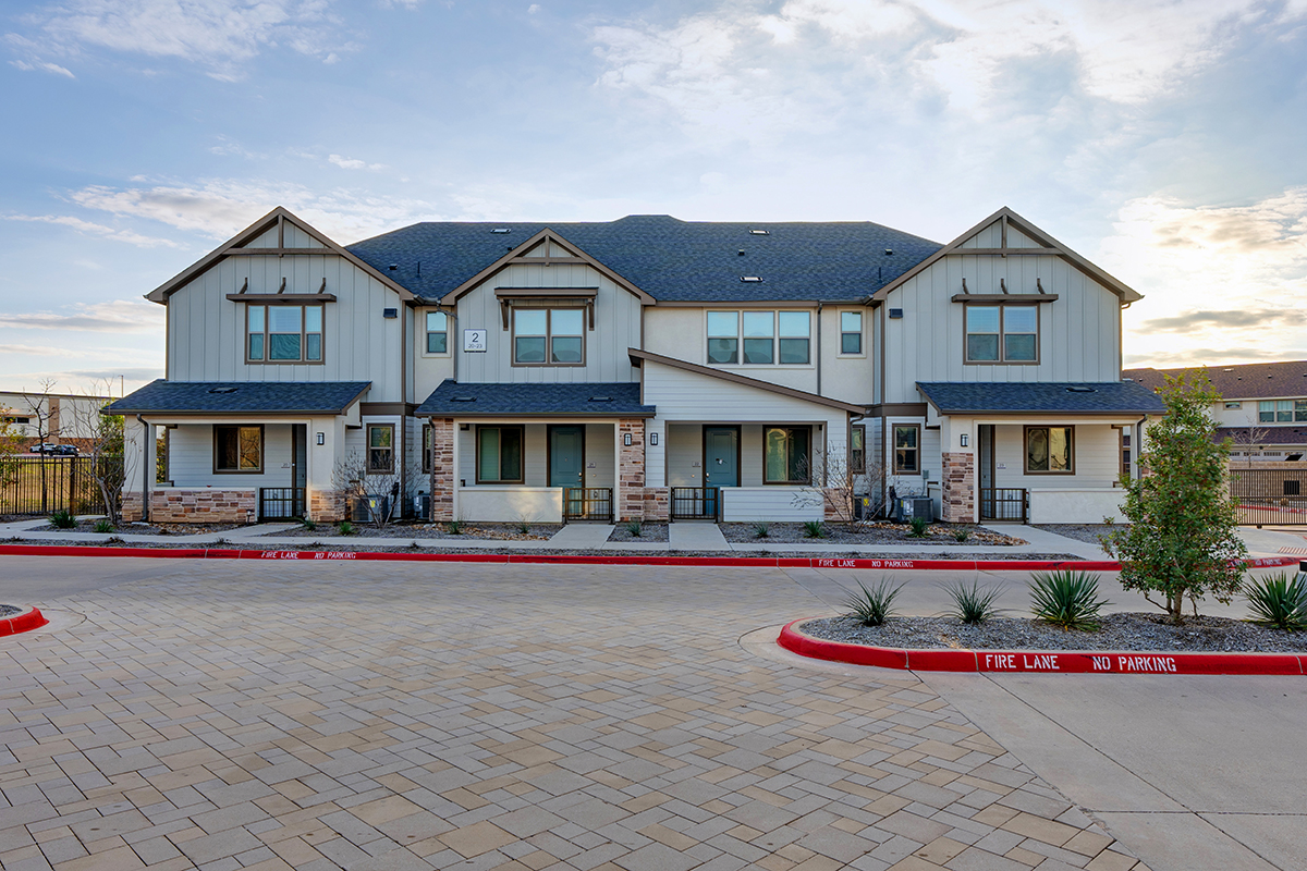 Row of two-story, luxury townhomes with front porches and blue front doors.