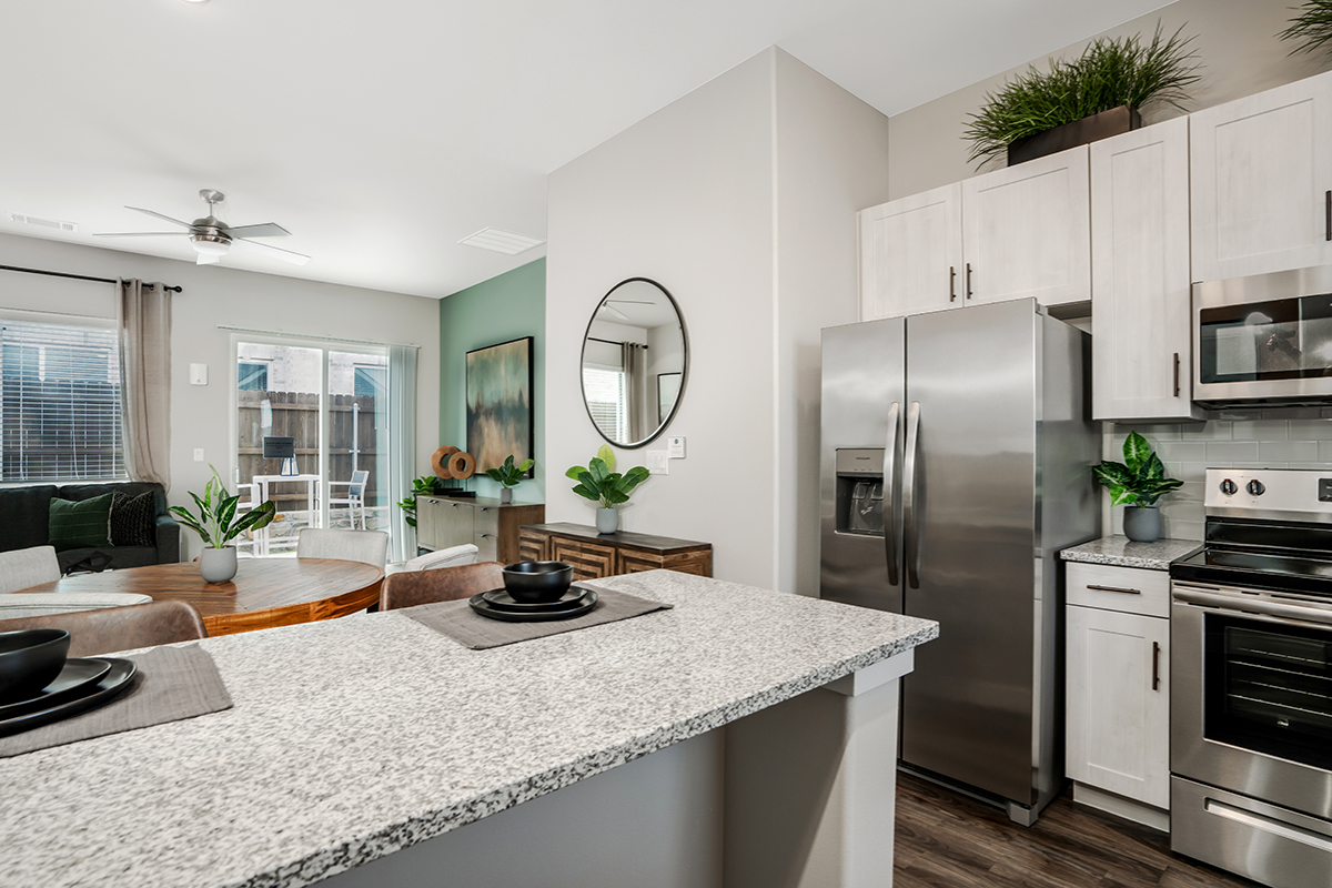 Modern kitchen with white cabinets, stainless steel appliances, and blue and gray accent colors.