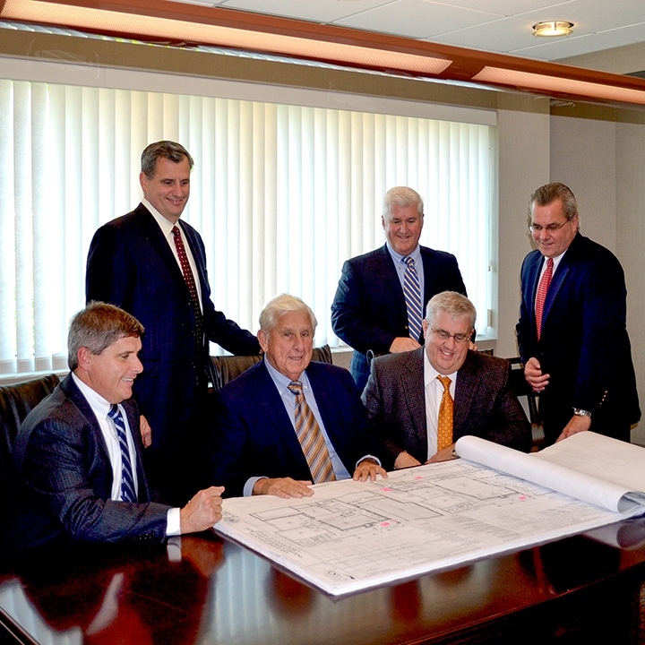 six bbl leadership staff looking over blueprints at a conference room table