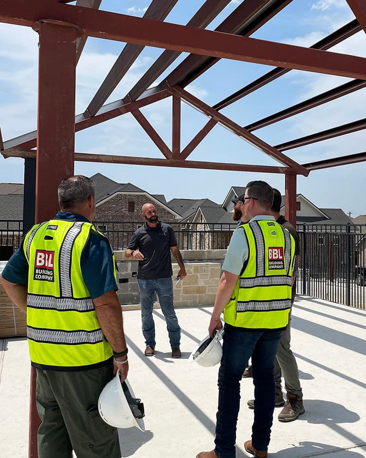 five bbl building staff members talking on a balcony at a built to rent construction site