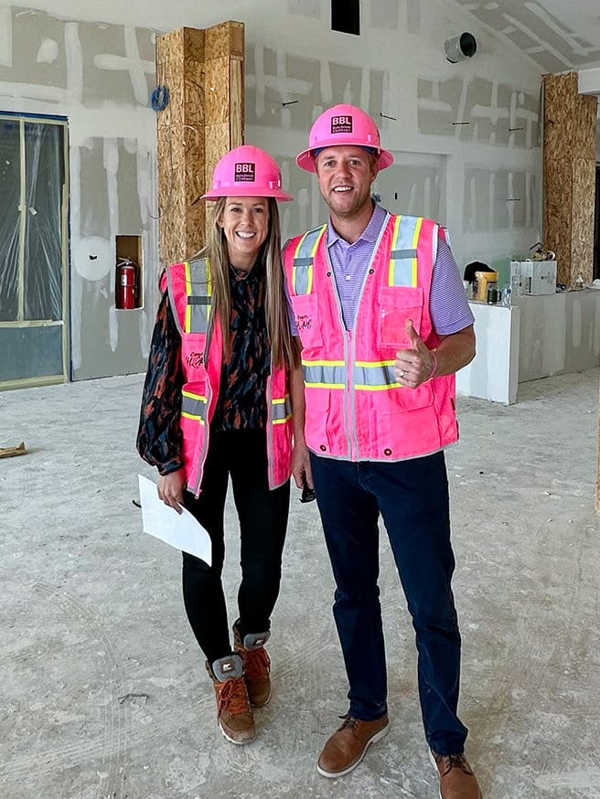two bbl staff members in a building under construction in pink hard hats and safety vests
