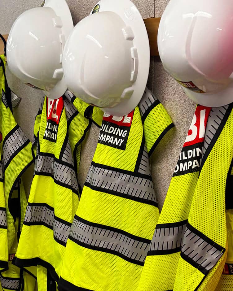 bbl construction safety vests and hard hats hung up on the wall