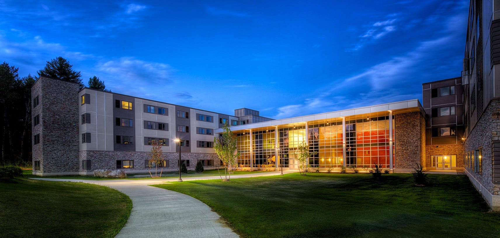 a commercial building lit up at night with large windows in the front and small windows down each wing