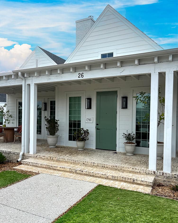 a brick front porch on a white house in a build to rent community built by bbl
