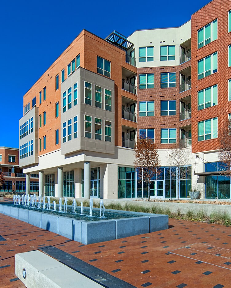 a brick multifamily apartment complex with a fountain in the front