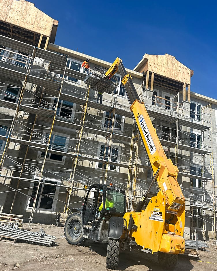 a human lift machine taking bbl staff up to a building with framing